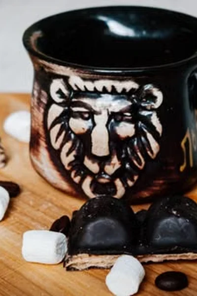 black ceramic mug with a hand-painted lion face