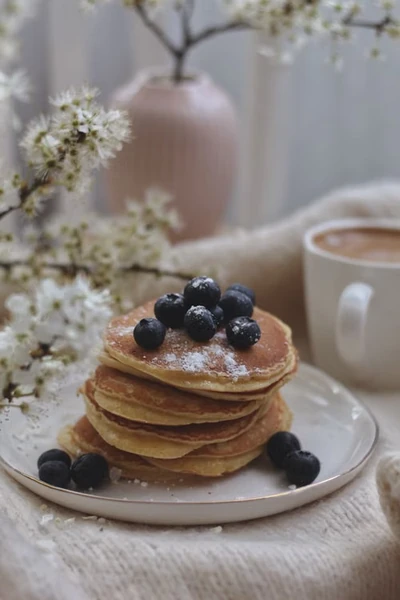Stack of fresh blueberry pancakes with a cup of coffee