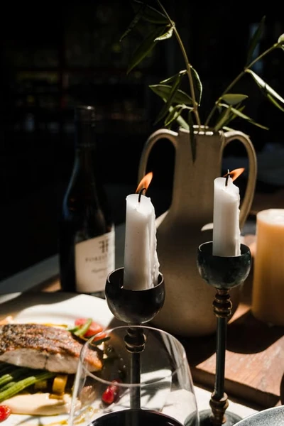 Candlelit dinner place setting with wine glass and greenery