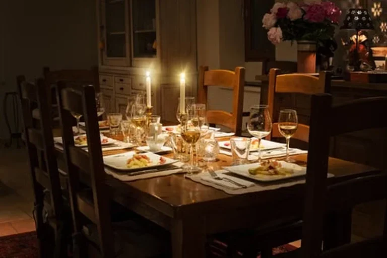 Candlelit dining table set with plates, glasses, and flowers