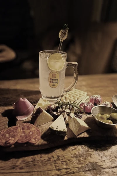 Charcuterie board with cheese, salami, olives, and a cold drink