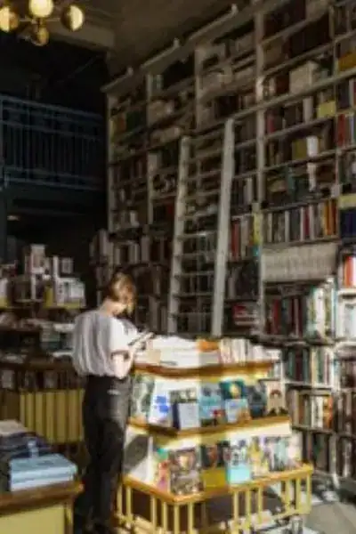 Young adult browsing an independent bookstore with tall bookshelves