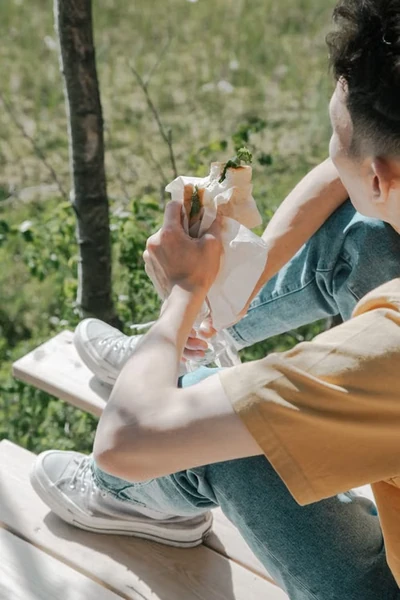 young guy with a packed lunch eating outside