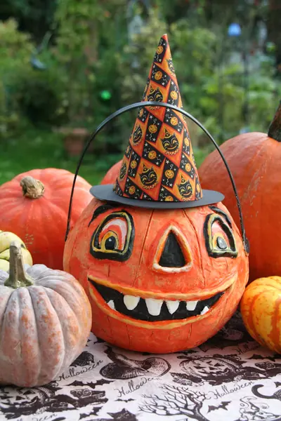 cute painted pumpkin with a tall hat on a table full of pumpkins