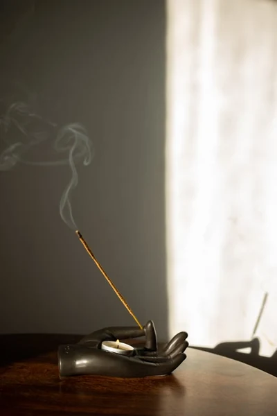 incense and tealight burning on a hand shaped metallic holder
