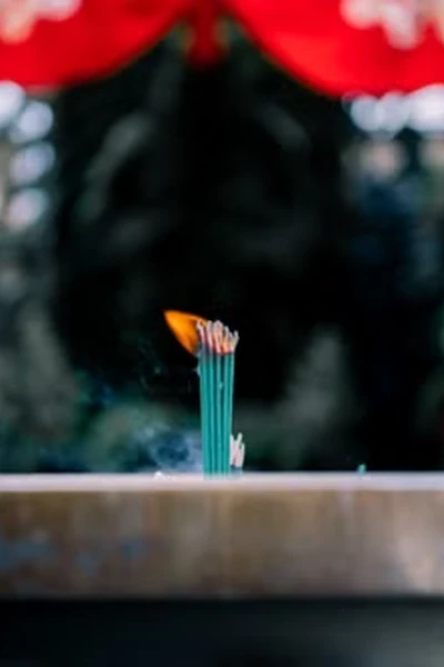 bundle of teal incense sticks burning in a metal incense holder