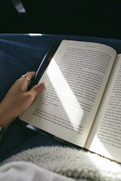 Person reading an open book in a patch of sunlight