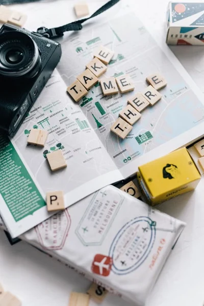 Travel planning setup with a map, camera, passport, and letter tiles