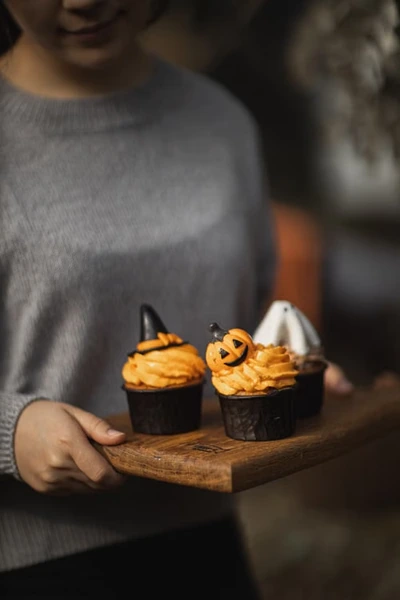 Pumpkin cupcakes decorated with Halloween toppers on a wooden board