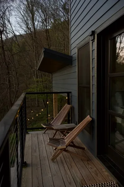 Two wooden chairs on a quiet porch at dusk overlooking the trees