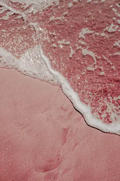 Ocean waves washing over pink sand