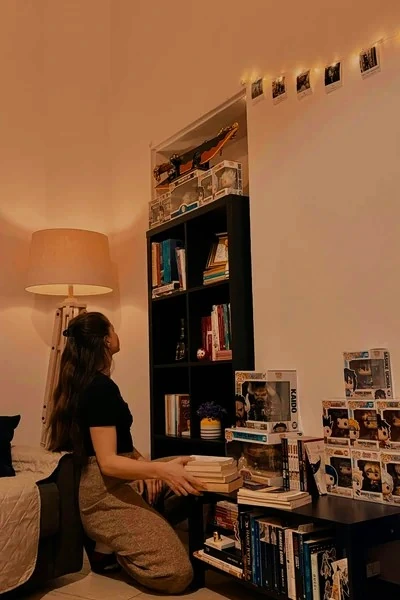Woman organizing books and keepsakes on a bedroom bookshelf