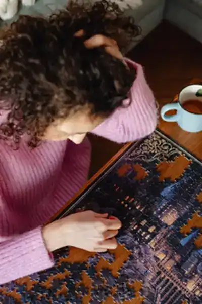 girl in pink sweater sitting at a table working on a puzzle